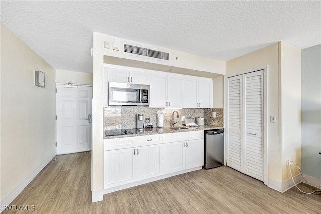 kitchen with backsplash, stainless steel appliances, light wood-type flooring, and white cabinets