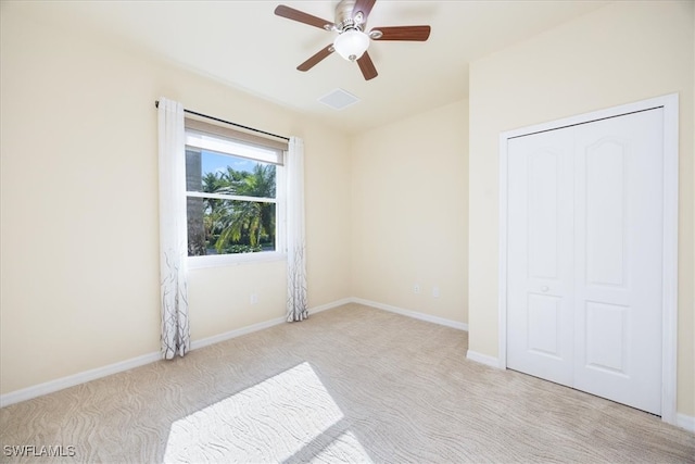 unfurnished bedroom featuring light carpet, a closet, and ceiling fan