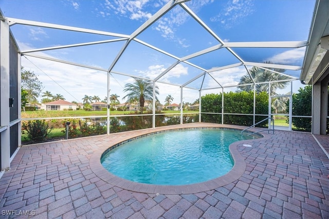 view of swimming pool with glass enclosure, a water view, and a patio