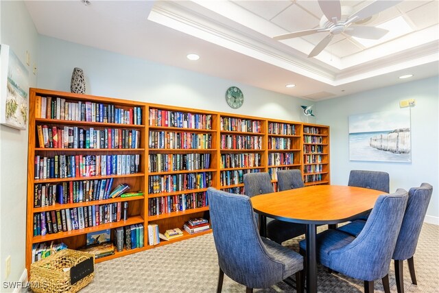 carpeted dining room featuring a tray ceiling, ceiling fan, and ornamental molding