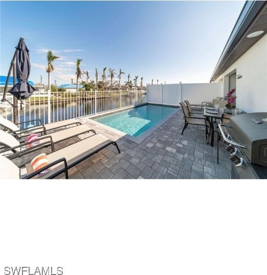 view of swimming pool featuring a patio, a water view, and area for grilling