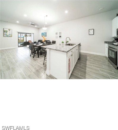 kitchen with white cabinets, sink, a kitchen island with sink, decorative light fixtures, and stainless steel appliances