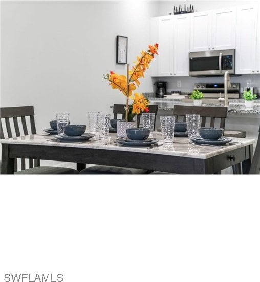 kitchen featuring light stone countertops, stainless steel appliances, and white cabinets