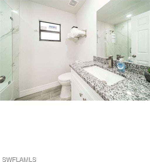 bathroom featuring walk in shower, vanity, and toilet