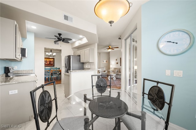 tiled dining room featuring ceiling fan with notable chandelier