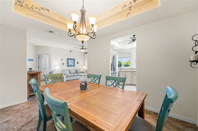 dining space featuring sink, ceiling fan with notable chandelier, and a raised ceiling