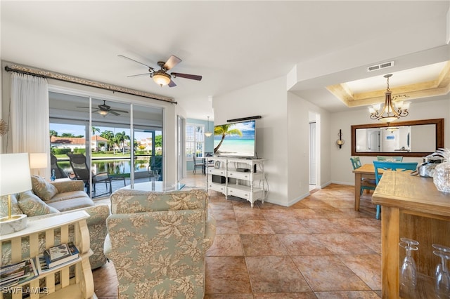 living room with a raised ceiling and ceiling fan with notable chandelier