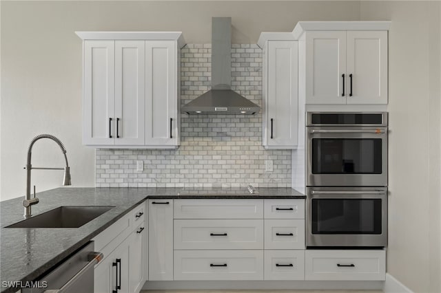 kitchen with white cabinets, sink, and wall chimney range hood