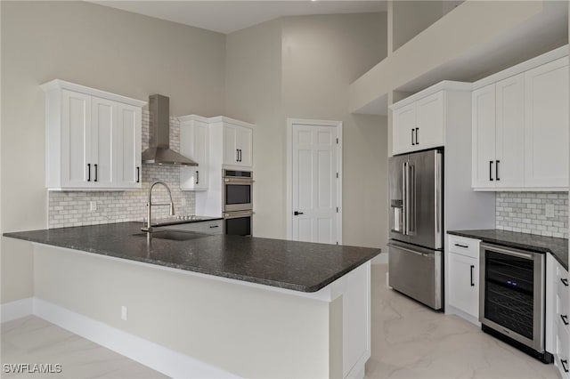 kitchen with appliances with stainless steel finishes, wall chimney range hood, wine cooler, and kitchen peninsula