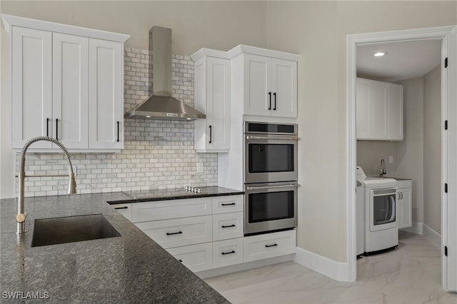 kitchen featuring white cabinetry, stainless steel double oven, sink, and wall chimney range hood