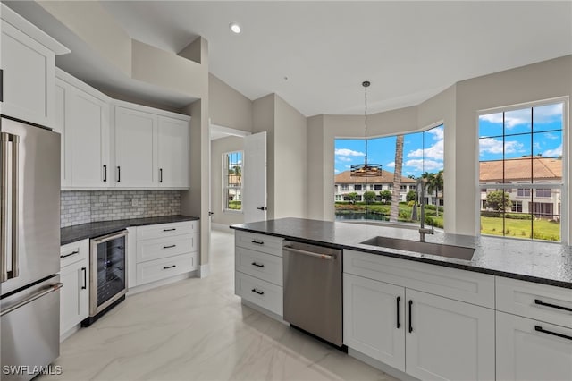 kitchen featuring decorative light fixtures, sink, white cabinets, beverage cooler, and stainless steel appliances