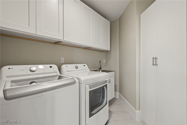 laundry area with cabinets, separate washer and dryer, and sink