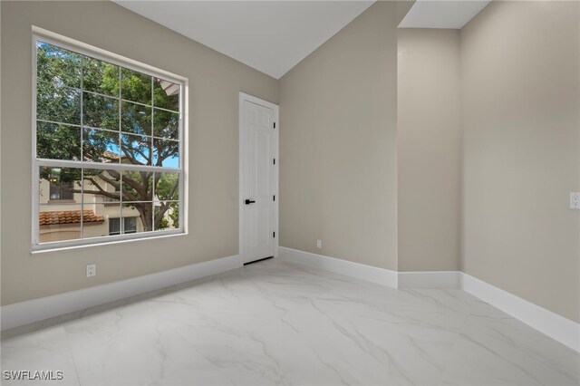 164 Colonade Cir Unit 1307, Naples, FL 34103 - spare room with baseboards, marble finish floor, and vaulted ceiling
