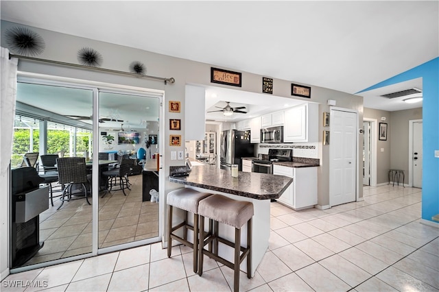 kitchen with a breakfast bar area, appliances with stainless steel finishes, kitchen peninsula, white cabinetry, and ceiling fan