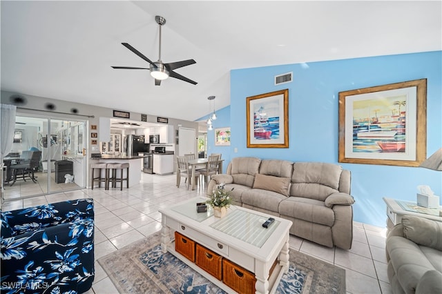 living room with ceiling fan, vaulted ceiling, and light tile patterned flooring