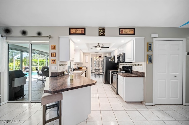 kitchen with white cabinetry, stainless steel appliances, kitchen peninsula, sink, and ceiling fan