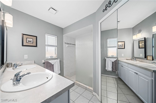 bathroom featuring vanity, a tile shower, and tile patterned flooring