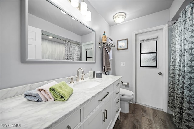 bathroom featuring hardwood / wood-style floors, a shower with curtain, toilet, and vanity