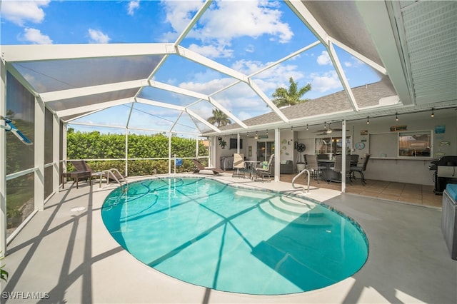 view of swimming pool featuring ceiling fan, a patio area, and glass enclosure