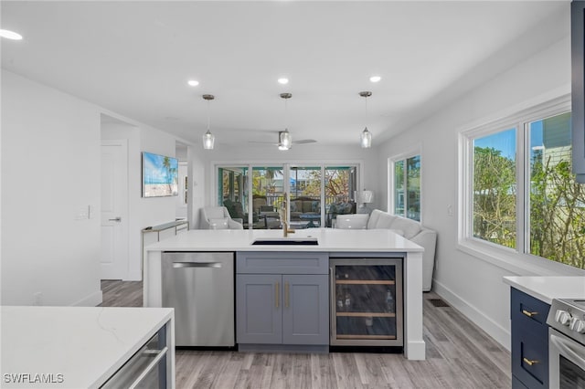 kitchen with beverage cooler, stainless steel appliances, open floor plan, and decorative light fixtures