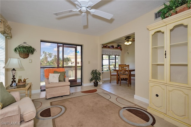 living room with baseboards, ceiling fan, visible vents, and light tile patterned floors