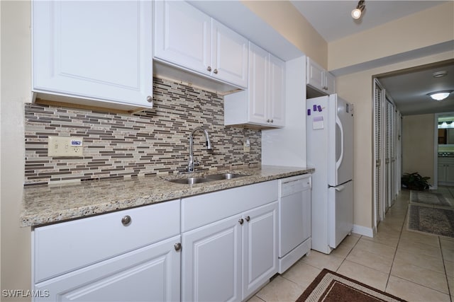 kitchen with light tile patterned flooring, white cabinetry, a sink, and white appliances