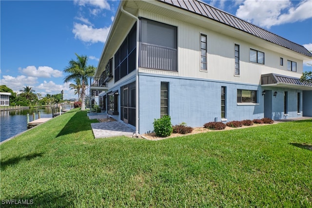 view of home's exterior with a water view and a yard