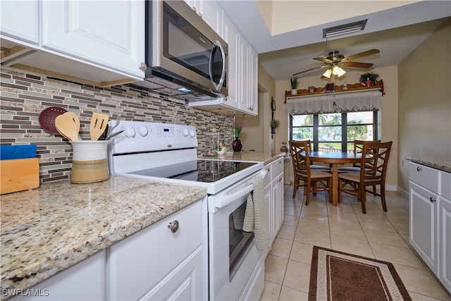 kitchen with stainless steel microwave, light tile patterned floors, visible vents, white cabinets, and electric range