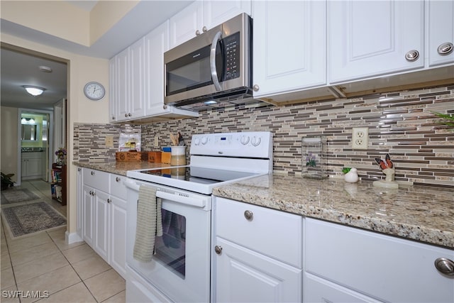 kitchen featuring light tile patterned flooring, stainless steel microwave, electric stove, white cabinets, and decorative backsplash
