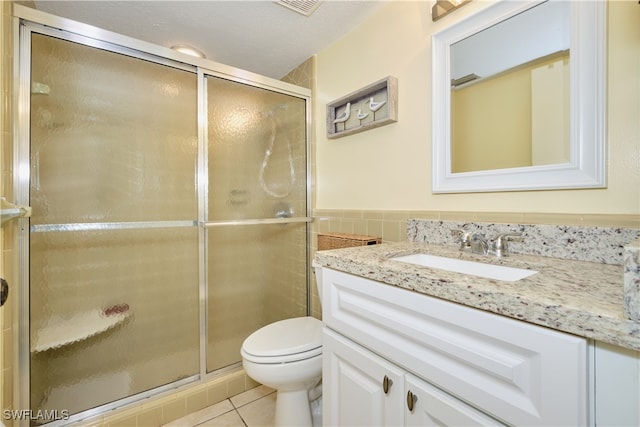 bathroom featuring vanity, a textured ceiling, tile patterned flooring, toilet, and an enclosed shower