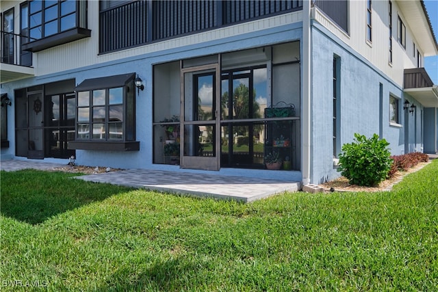 exterior space featuring stucco siding and a lawn
