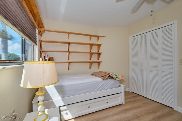 bedroom with ceiling fan, light hardwood / wood-style floors, and a closet