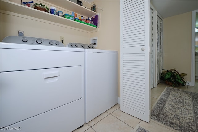 washroom with washing machine and clothes dryer, light tile patterned flooring, and laundry area