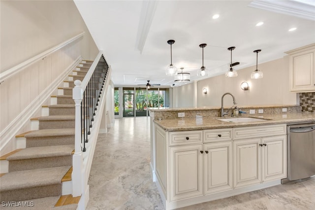 kitchen featuring cream cabinets, hanging light fixtures, sink, and stainless steel dishwasher