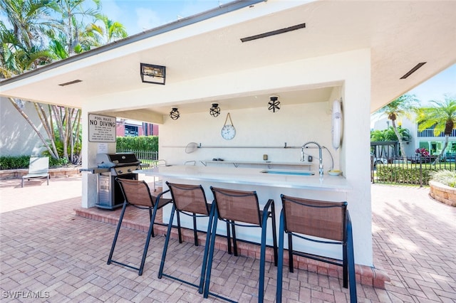 view of patio with area for grilling, an outdoor kitchen, and an outdoor wet bar