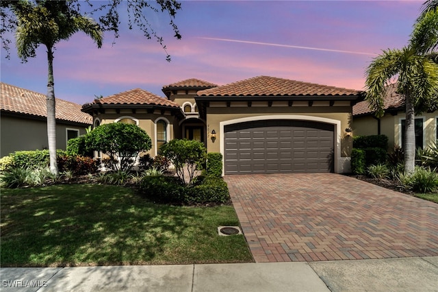 mediterranean / spanish-style home featuring a garage and a yard