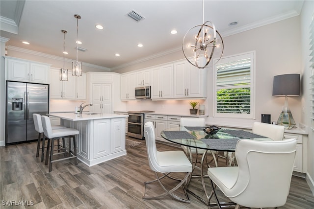 kitchen featuring appliances with stainless steel finishes, a chandelier, dark hardwood / wood-style floors, an island with sink, and pendant lighting