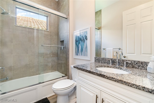 full bathroom with wood-type flooring, toilet, combined bath / shower with glass door, and vanity