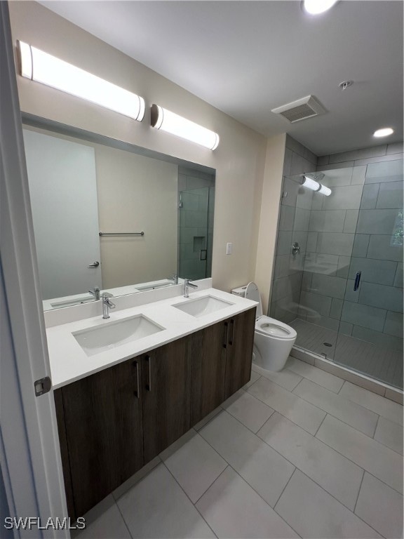 bathroom with vanity, toilet, tile patterned floors, and a shower with door