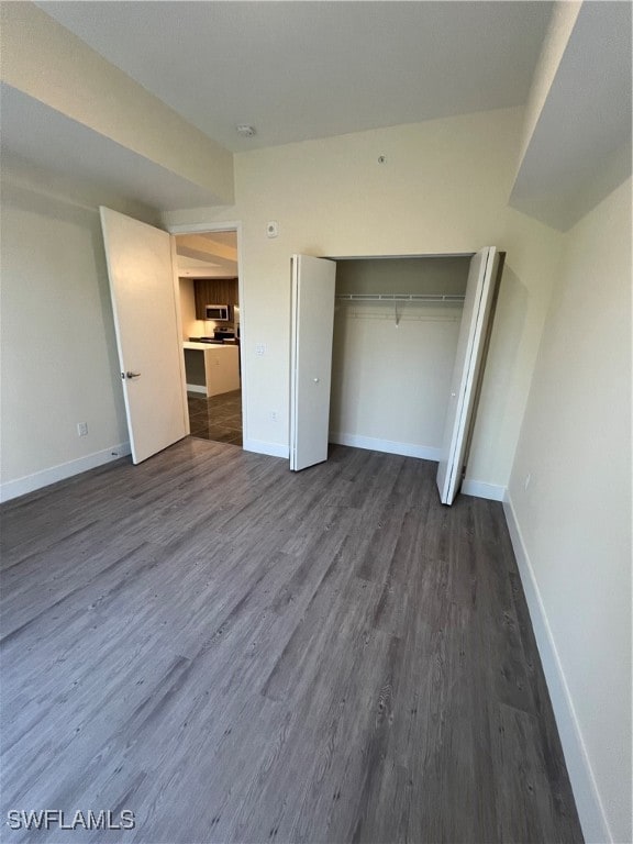 unfurnished bedroom with dark wood-type flooring and a closet