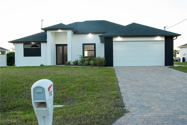 prairie-style house featuring decorative driveway, roof with shingles, stucco siding, an attached garage, and a front yard