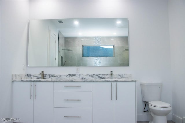 bathroom with double vanity, recessed lighting, toilet, a sink, and tiled shower