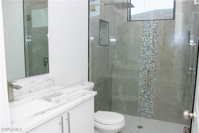 bathroom featuring a shower stall, toilet, and vanity