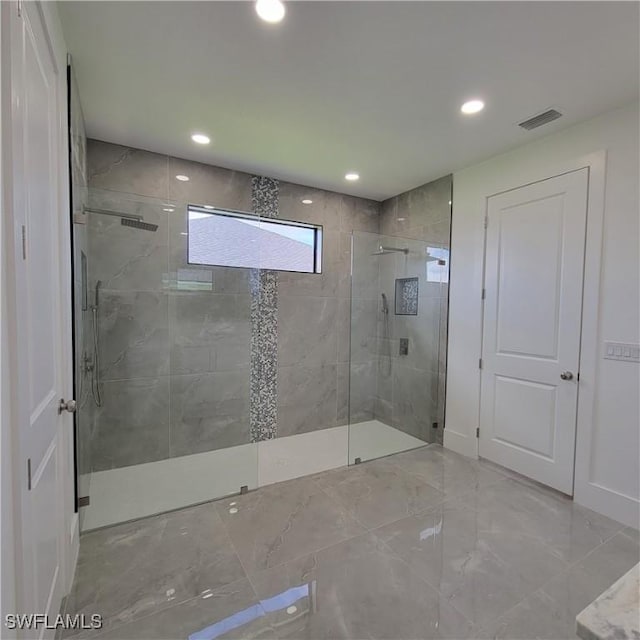 bathroom featuring marble finish floor, visible vents, a tile shower, and recessed lighting