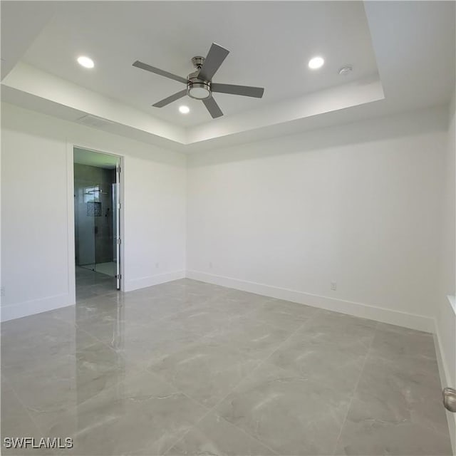 unfurnished room with baseboards and a tray ceiling