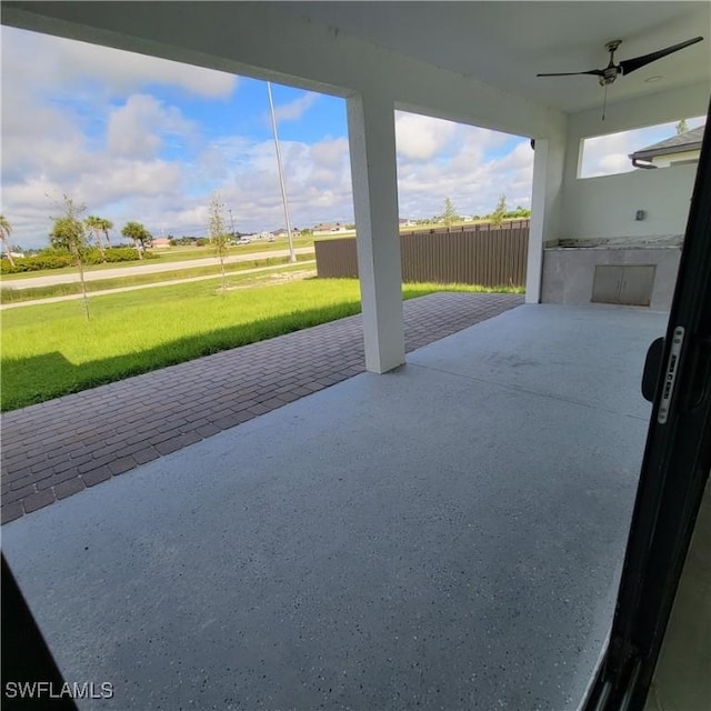 view of patio with fence, an outdoor kitchen, and a ceiling fan