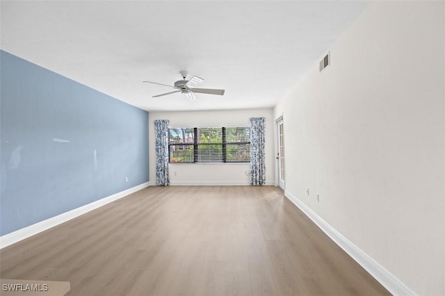 empty room with visible vents, ceiling fan, baseboards, and wood finished floors