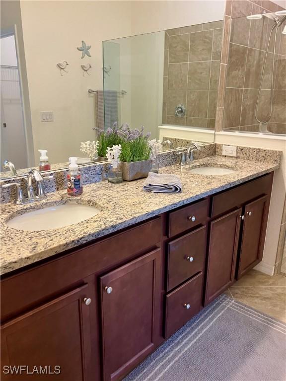 bathroom with tile patterned flooring, vanity, and tiled shower