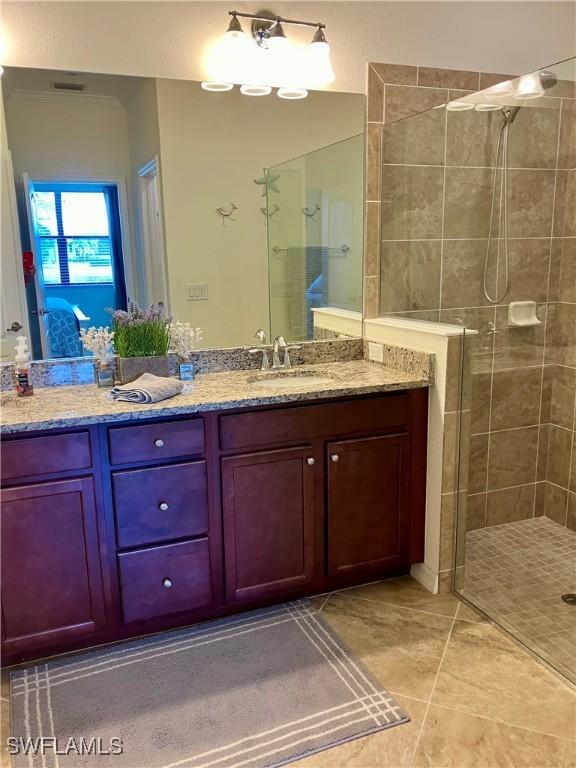 bathroom with tile patterned floors, vanity, and a tile shower