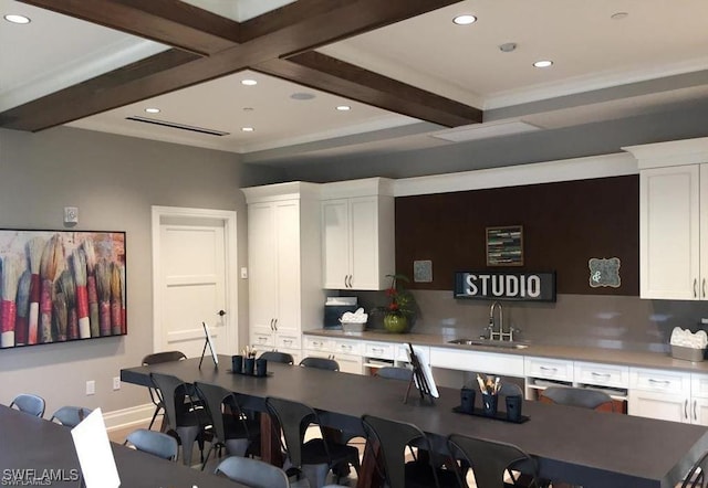 kitchen featuring white cabinets, beam ceiling, a kitchen breakfast bar, and sink